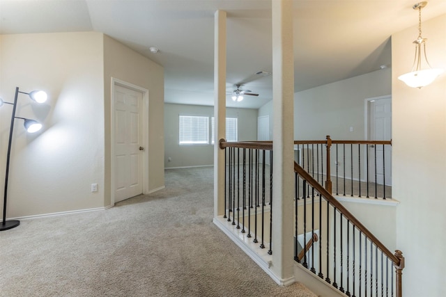 hallway featuring baseboards, an upstairs landing, and carpet