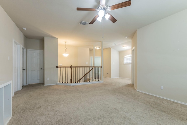 empty room featuring light colored carpet, a ceiling fan, baseboards, and visible vents