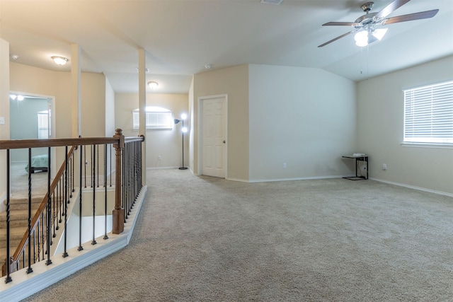 carpeted empty room featuring ceiling fan, vaulted ceiling, baseboards, and visible vents