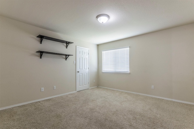 empty room featuring baseboards and light colored carpet
