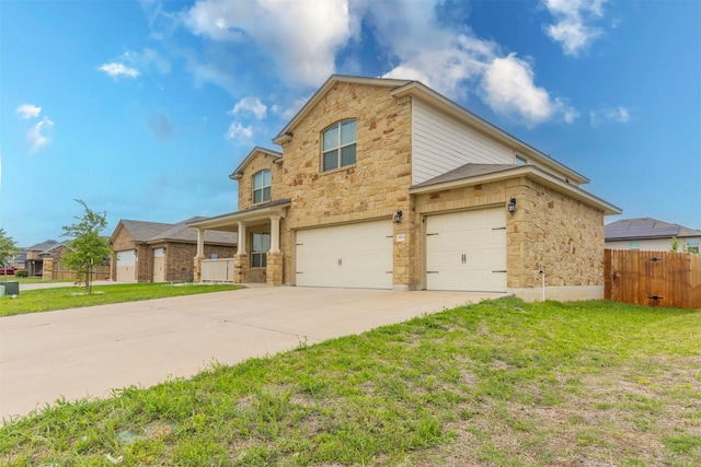 traditional-style home with fence, an attached garage, a front lawn, stone siding, and concrete driveway
