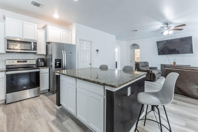 kitchen with light wood-type flooring, arched walkways, appliances with stainless steel finishes, and visible vents