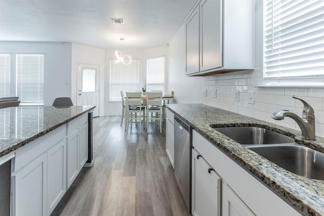kitchen with visible vents, tasteful backsplash, a sink, light wood-style flooring, and dishwasher