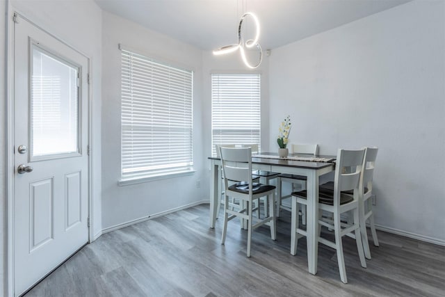 dining space featuring baseboards, wood finished floors, and a notable chandelier
