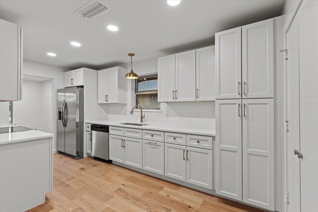 kitchen featuring stainless steel appliances, a sink, recessed lighting, white cabinets, and light countertops