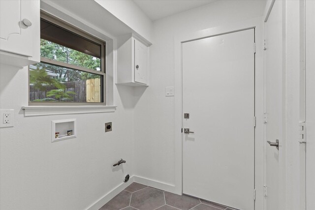 clothes washing area with cabinet space, hookup for an electric dryer, hookup for a washing machine, dark tile patterned flooring, and baseboards