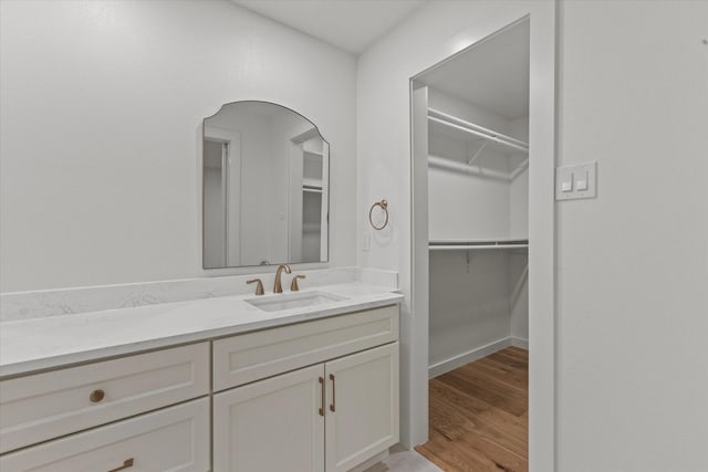 1717 Anderson St, Irving, TX 75062 - bathroom featuring vanity, a walk in closet, wood finished floors, and baseboards