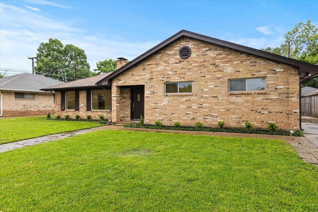 view of front of house with brick siding, a front lawn, and a chimney