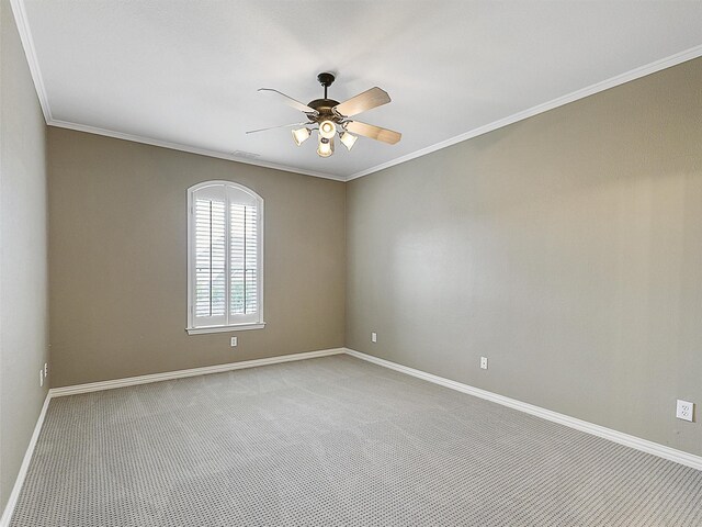 carpeted spare room featuring crown molding, a ceiling fan, and baseboards