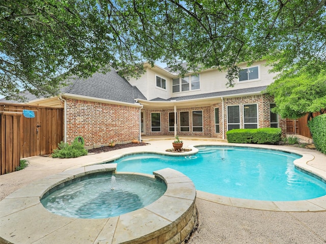 view of pool featuring a patio, fence, and a pool with connected hot tub