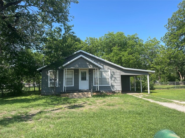 bungalow-style home with a porch, fence, a front yard, and a carport