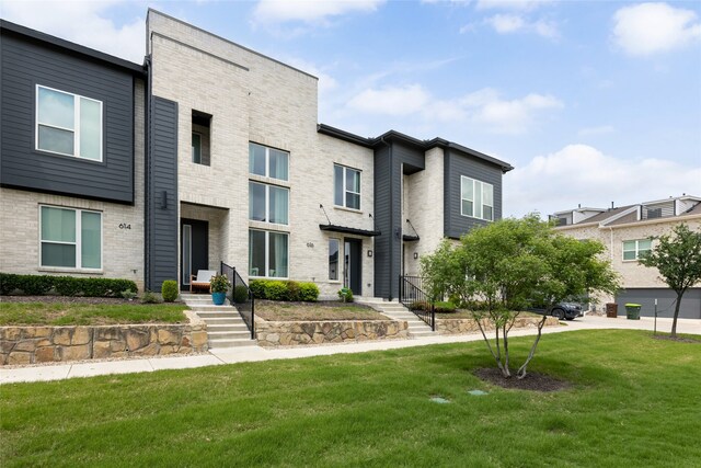 contemporary house featuring brick siding and a front yard