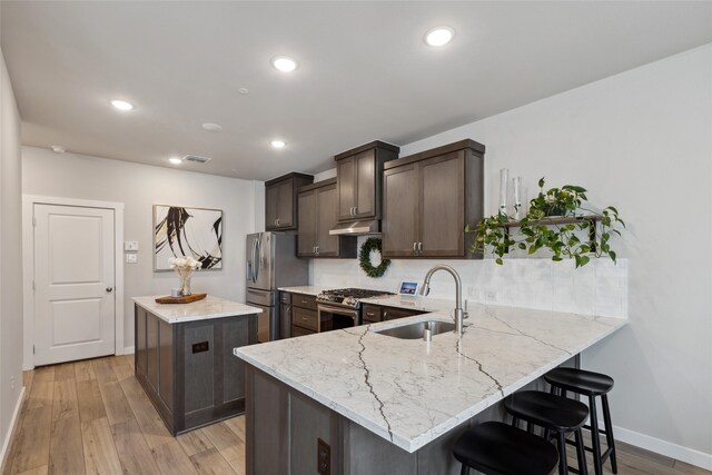 kitchen with a kitchen island, appliances with stainless steel finishes, tasteful backsplash, dark brown cabinets, and a sink