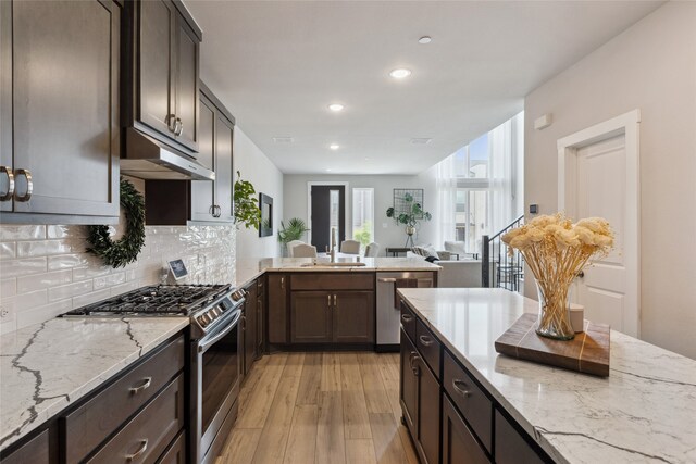 kitchen with a sink, under cabinet range hood, light wood-style floors, stainless steel appliances, and recessed lighting