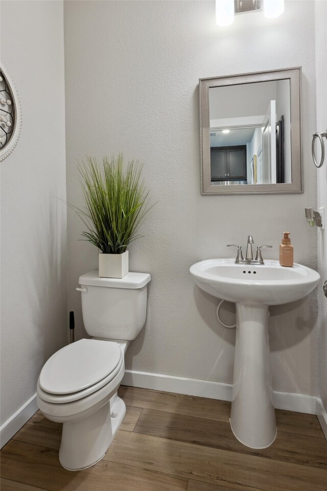 bathroom featuring toilet, baseboards, and wood finished floors