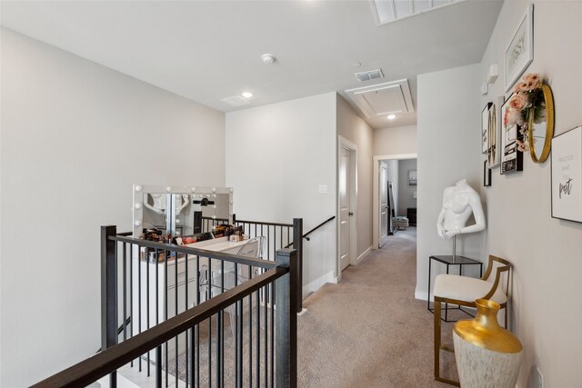 corridor featuring visible vents, an upstairs landing, light carpet, and attic access