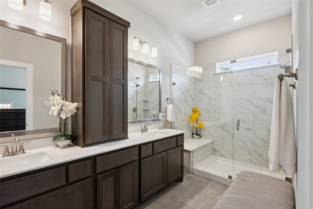 full bath featuring double vanity, visible vents, a marble finish shower, and a sink