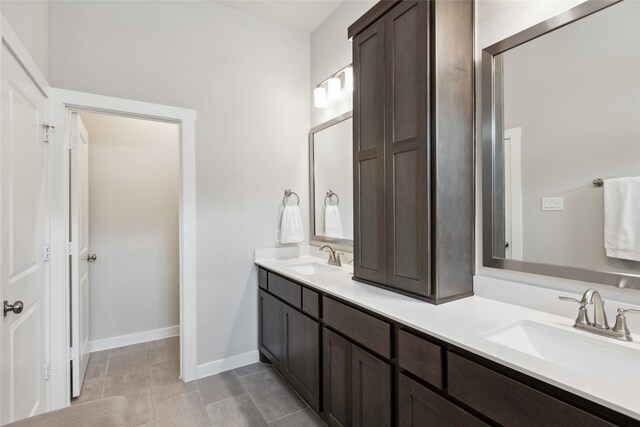 bathroom with double vanity, a sink, and baseboards