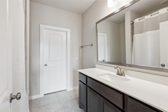 full bathroom with tile patterned floors, baseboards, and vanity