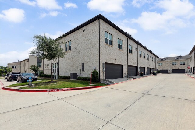 view of property exterior with an attached garage, central AC, and brick siding