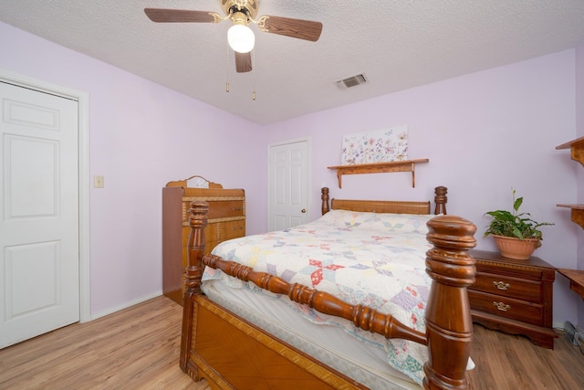 bedroom featuring visible vents, baseboards, light wood-type flooring, a textured ceiling, and a ceiling fan