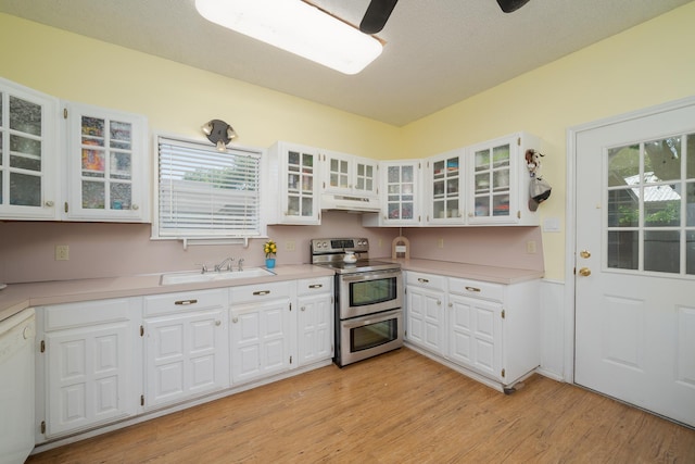 kitchen featuring a healthy amount of sunlight, white cabinets, under cabinet range hood, and double oven range