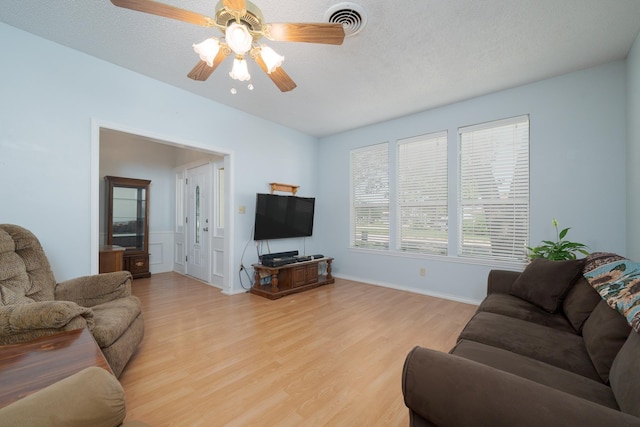 living room featuring light wood-style floors, baseboards, ceiling fan, and visible vents