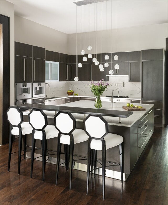 kitchen featuring a large island with sink, modern cabinets, a breakfast bar, and tasteful backsplash