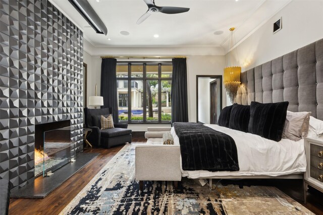 bedroom featuring crown molding, visible vents, a large fireplace, and wood finished floors