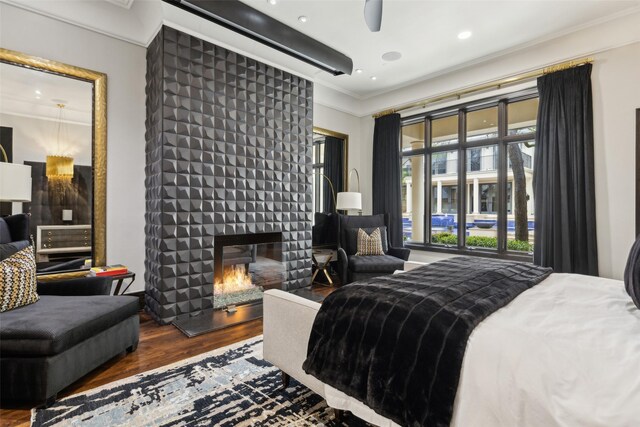 bedroom with crown molding, a multi sided fireplace, recessed lighting, and wood finished floors