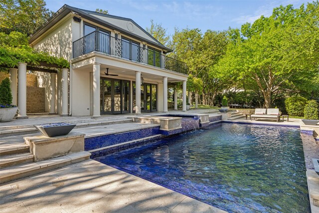 back of property featuring a patio, a ceiling fan, an outdoor pool, and a balcony