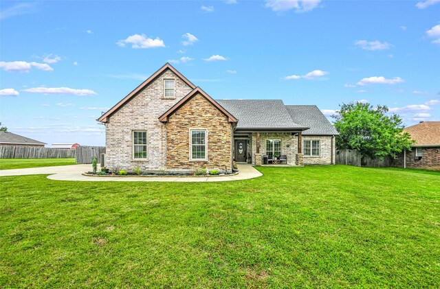 view of front of property with brick siding, fence, a front yard, and roof with shingles