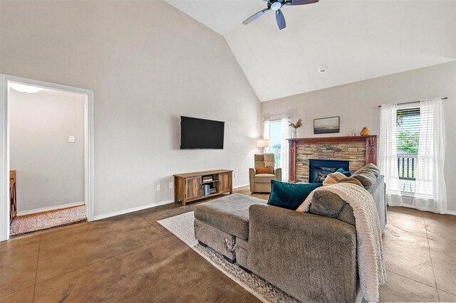 living area featuring a stone fireplace, a ceiling fan, baseboards, and high vaulted ceiling