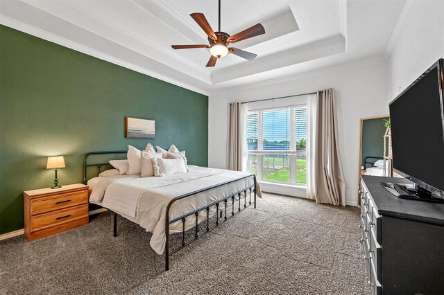 bedroom with ceiling fan, crown molding, a raised ceiling, baseboards, and carpet flooring