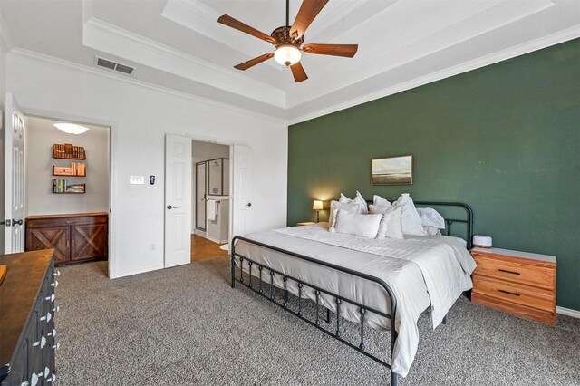 carpeted bedroom with crown molding, ceiling fan, baseboards, a tray ceiling, and visible vents