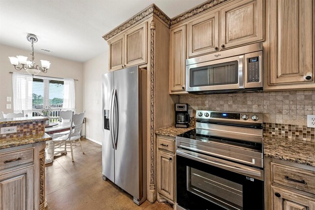 kitchen featuring appliances with stainless steel finishes, decorative backsplash, dark stone countertops, and a notable chandelier