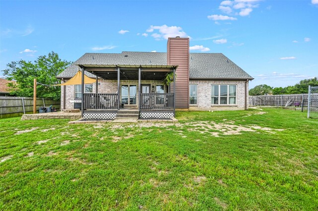 back of property featuring a yard, a deck, brick siding, and a fenced backyard