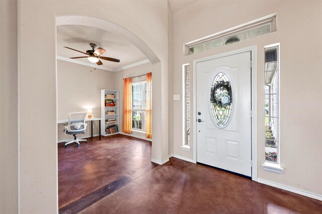entrance foyer with arched walkways, a ceiling fan, baseboards, finished concrete floors, and ornamental molding