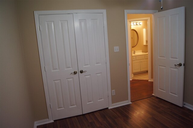 unfurnished bedroom featuring baseboards, dark wood finished floors, and a closet