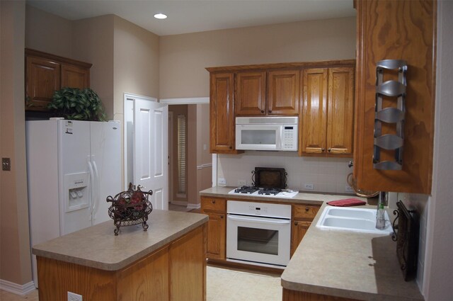 kitchen featuring brown cabinets, a sink, white appliances, light countertops, and tasteful backsplash