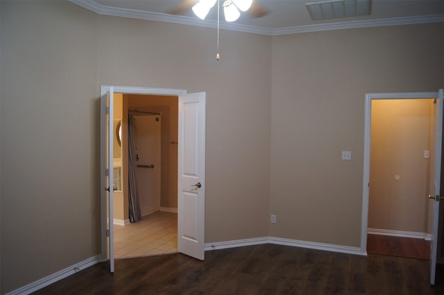 unfurnished room featuring crown molding, a ceiling fan, baseboards, wood finished floors, and visible vents