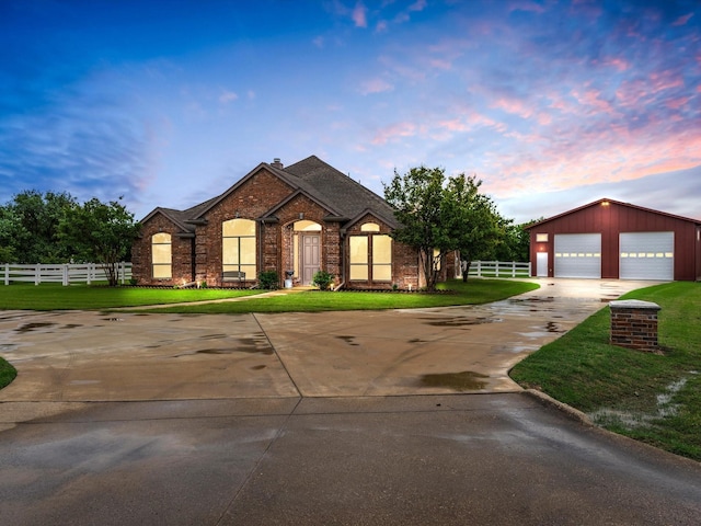 single story home featuring driveway, a detached garage, brick siding, fence, and a front lawn