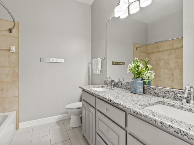 full bathroom with double vanity, a sink, baseboards, and toilet