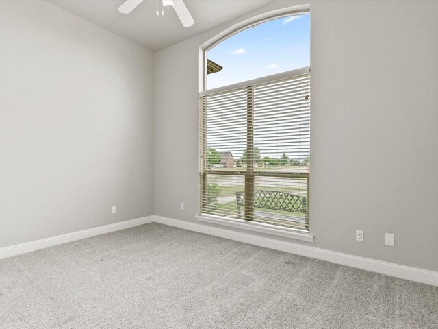 spare room with carpet floors, baseboards, and ceiling fan