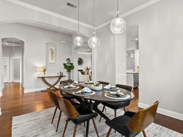 dining area with arched walkways, baseboards, wood finished floors, and visible vents