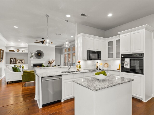 kitchen featuring ceiling fan, a lit fireplace, a sink, black appliances, and a peninsula