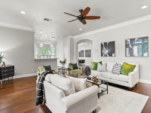 living room featuring crown molding, arched walkways, baseboards, and a ceiling fan