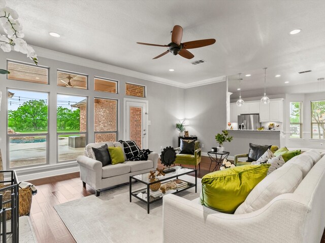 living area featuring ceiling fan, visible vents, crown molding, wood finished floors, and recessed lighting