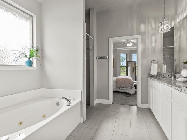 full bath featuring vanity, a tub with jets, baseboards, ceiling fan, and ensuite bath