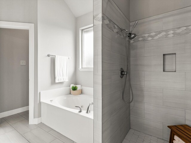 bathroom featuring tile patterned flooring, lofted ceiling, baseboards, tiled shower, and a bath